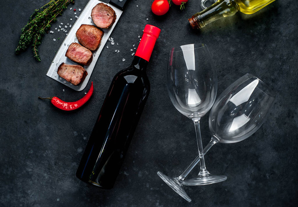 ψητές φέτες κρέατος και κόκκινο κρασί μπουκάλι με ποτήρια σε ρουστίκ φόντο - Φωτογραφία, εικόνα