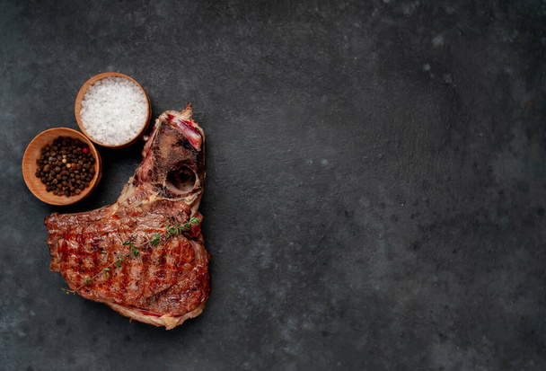 Ribeye grill hús steak sóval és borssal tálak rusztikus asztal háttér - Fotó, kép