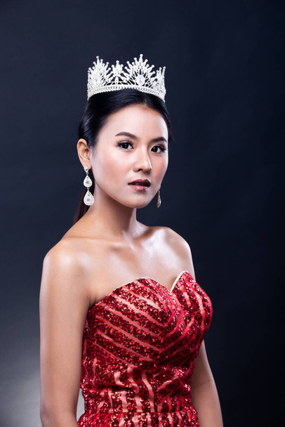 Portret Miss konkursu piękności w czerwonym cekinem Wieczorna suknia balowa długa sukienka z blaskiem światła Diamentowa korona, azjatycka moda kobieta tworzą czarne włosy, oświetlenie studio ciemne tło - Zdjęcie, obraz