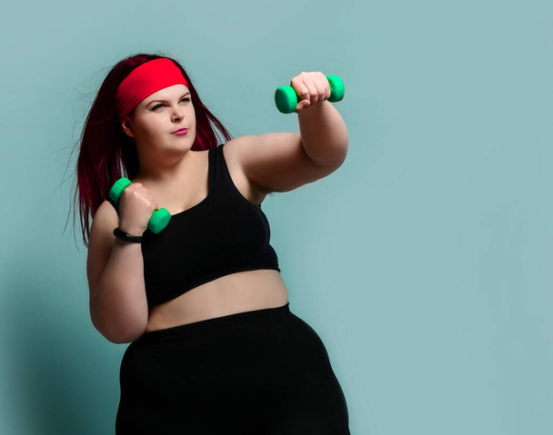Fitness spring diet weight loss concept. Concentrating plus-size overweight woman does punches with weights dumbbells  - Fotó, kép