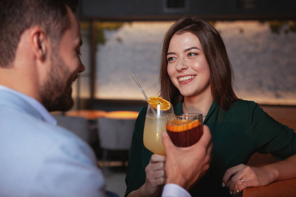 Beautiful cheerful woman enjoying night out with her boyfriend at cocktail bar. Couple celebrating anniversary - Photo, Image