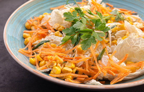 Σαλάτα λαχανικών με κινέζικο λάχανο, καρότα, καλαμπόκι και μαϊντανό με πράσινα κρεμμύδια. Απόθεμα σαλάτα φωτογραφία σε ένα μπλε πιάτο. - Φωτογραφία, εικόνα