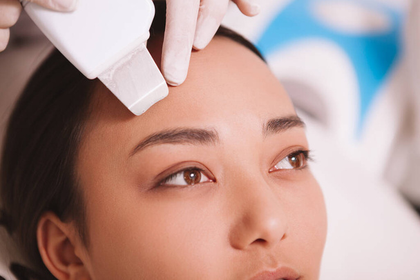 Plan recadré de femme asiatique se faire échographie nettoyage du visage par un cosmétologue
 - Photo, image