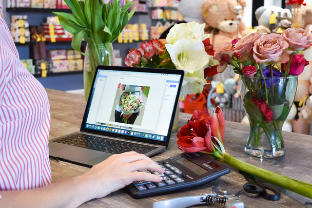 processing orders on a laptop. Small floral business. Salon of flowers and gifts - 写真・画像