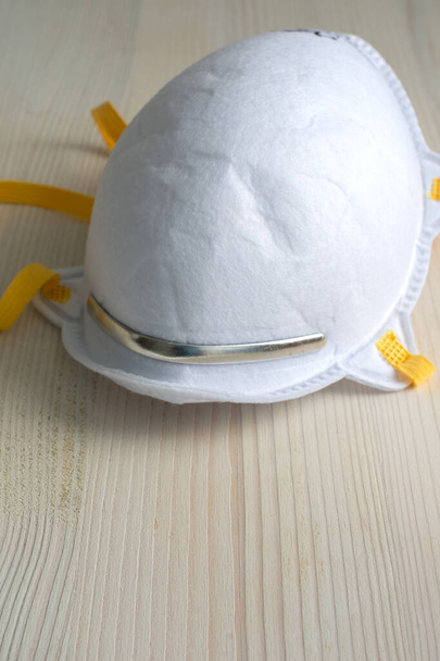 Gros plan du masque de protection blanc avec caoutchouc jaune, sur fond vertical en bois blanc avec espace de copie
 - Photo, image