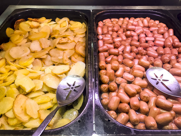 Τηγανητές φέτες πατάτας και μικρά βραστά λουκάνικα, πρωινό. Φωτογραφία στούντιο - Φωτογραφία, εικόνα