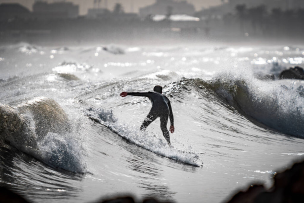 Υψηλή αντίθεση της αγνώριστη surfer surfing κοντά στην πόλη - Φωτογραφία, εικόνα