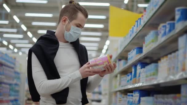 comprador con máscara protectora es la elección de alimentos para bebés en el supermercado
 - Metraje, vídeo