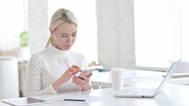 Giovane donna d'affari utilizzando smartphone in ufficio
 - Foto, immagini