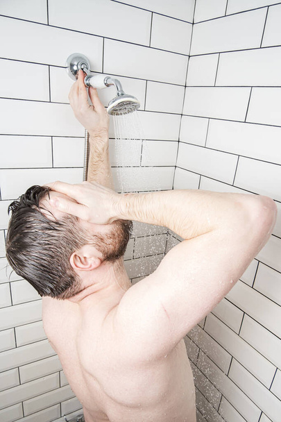 Homem caucasiano fica no chuveiro desfrutando de água morna. Conceito de descanso após um dia difícil
. - Foto, Imagem