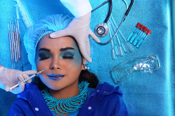 Creative Plastic Surgery on Blue Tone Fashion Patient Θηλυκό μοντέλο με εργαλεία ιατρικού εξοπλισμού, φωτιστικό στούντιο αντίγραφο χώρου, top view ιατρική σύριγγα χειρός - Φωτογραφία, εικόνα