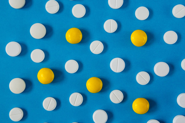 medicine and health, white and yellow pills on a blue background from above - Фото, зображення