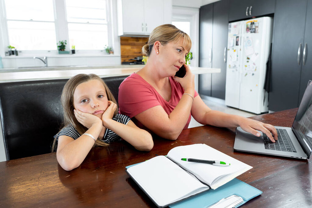 Coronavirus Outbreak schools and offices closing. Stressed mother coping with remote work and bored daughter. COVID-19 shutdowns and quarantines forces parents to work from home and homeschooling. - Photo, image