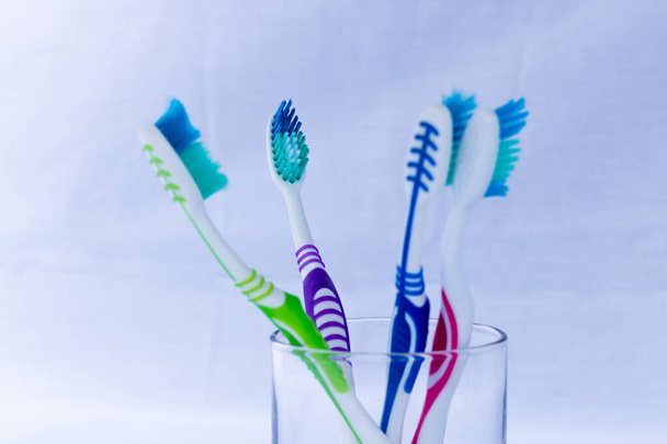 Cepillos de dientes de diferentes colores en una base y fondo blanco
 - Foto, Imagen