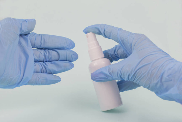 meisje met een antisepticum tegen bacteriën in blauwe rubberen handschoenen - Foto, afbeelding
