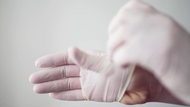 The doctor puts white protective gloves on his hands. A professional medical worker. Pandemic coronavirus and infection - Materiał filmowy, wideo