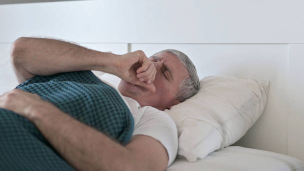Хворий чоловік середнього віку кашель під час сну в ліжку
 - Фото, зображення