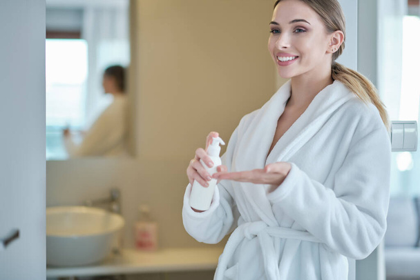 Hand sanitizing. woman in a bathrobe disinfects hands. virus protection - Foto, imagen