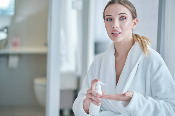 Hand sanitizing. woman in a bathrobe disinfects hands. virus protection - 写真・画像