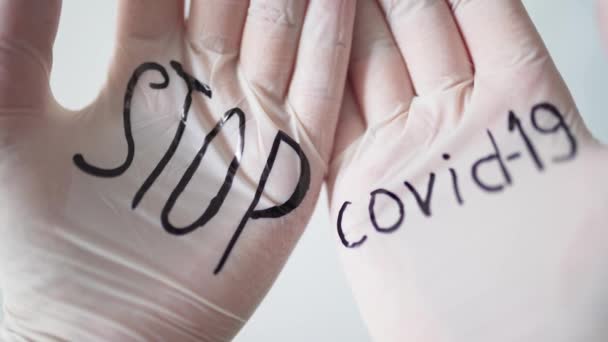 Black inscription on white medical gloves STOP covid-19. Health and medicine during the coronavirus pandemic. Close-up - Filmagem, Vídeo