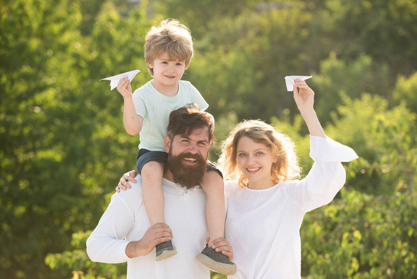 Family travel and vacation concept. Father carrying his son on shoulders. Parenthood and childhood concept. Kids playing with simple paper planes on sunny day. Family Time Together. - Photo, Image