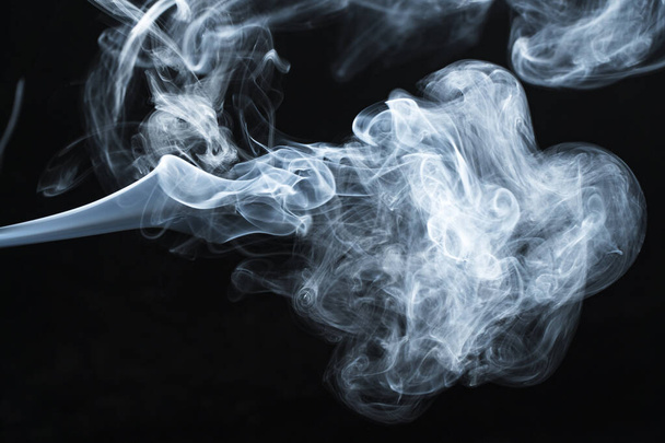 Background image of a wisp of smoke on a dark background. The texture of the flowing smoke. Frozen smoke on a dark background. Graphic resources dark backdrop. Texura of white clouds of fog. Curls of smoke frozen in motion. - Foto, afbeelding