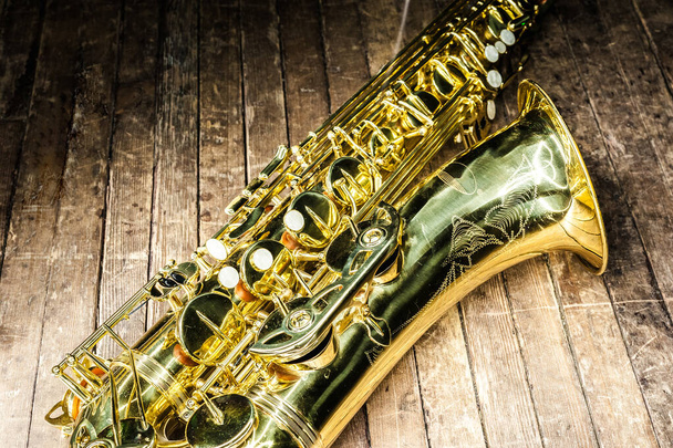 část pouzdra s kapsami a zvonky ze žlutého saxofonu na starém dřevěném povrchu - Fotografie, Obrázek