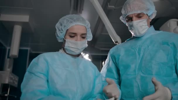 Dois cirurgiões de robes preparam equipamentos para cirurgia
 - Filmagem, Vídeo