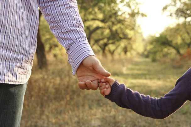 el padre sosteniendo la mano del niño con un fondo feliz - Foto, Imagen