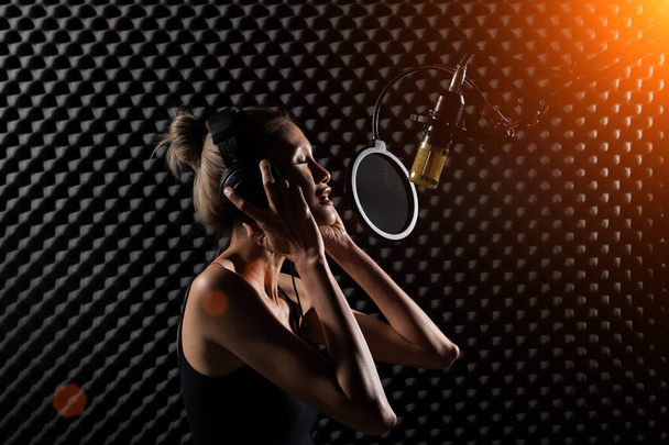 Mix Race худа жінка блондинка коротке волосся навушники співають пісню голосно з потужним звуком над повішеним мікрофонним конденсатором. Студія яєчного ящика з низьким освітленням тінь Звук Доказ Поглинання настінної кімнати
 - Фото, зображення