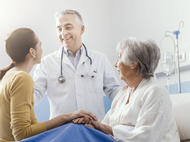 Szakmai mosolygós orvos találkozik egy idős beteg és lánya a kórházban, orvosi szolgáltatás koncepció - Fotó, kép