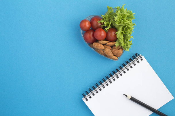 Notebook a zdravé svačinové potraviny na modrém pozadí. Horní pohled. Kopírovat prostor. - Fotografie, Obrázek
