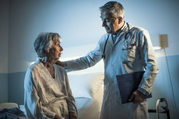 Caring doctor comforting a senior patient at the hospital at night, senior care concept - Fotografie, Obrázek