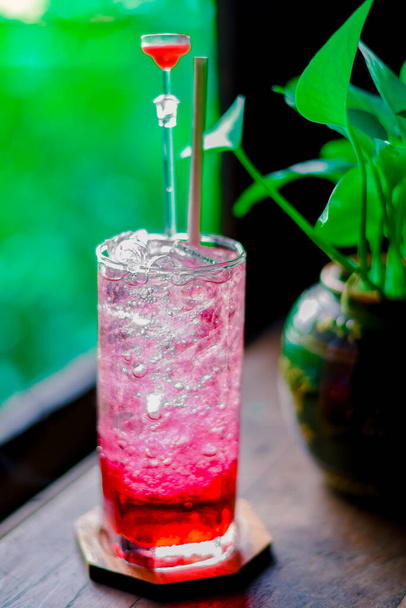 червоний сік вода з білої содової в склянці на дерев'яному столі в кафе. Літній напій
 - Фото, зображення