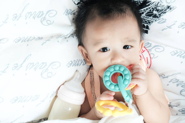 Asiático bebé niño acostado en blanco manta con goma mordida mirar hacia abajo ver
 - Foto, Imagen