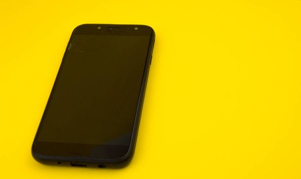 Cell phone with broken screen on yellow background. - Photo, Image