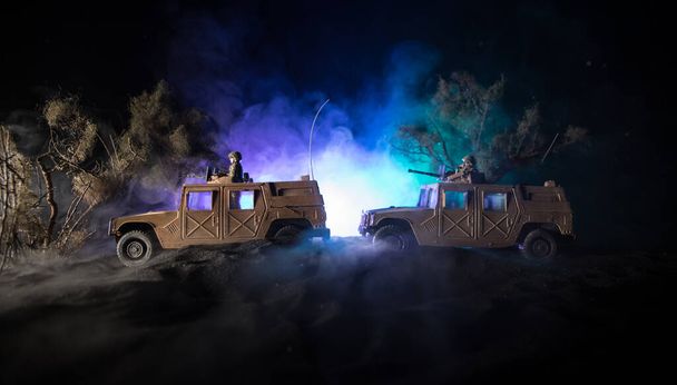 War Concept. Battle scene on war fog sky background, Fighting silhouettes Below Cloudy Skyline at night. Army vehicle with soldiers artwork decoration. Selective focus - Photo, Image