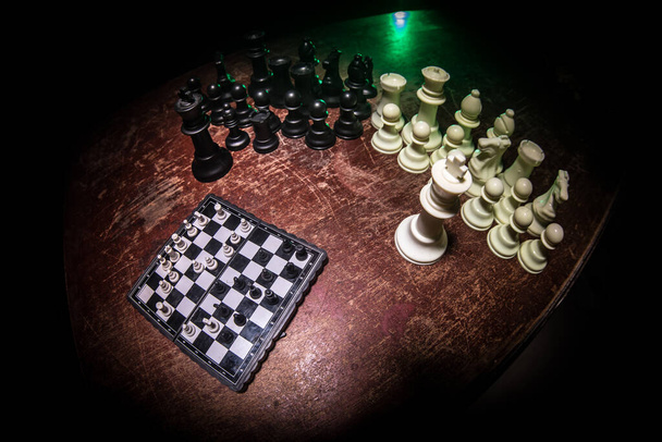 Chess board game concept of business ideas and competition. Chess figures on a dark background with smoke and fog. Selective focus - Photo, Image