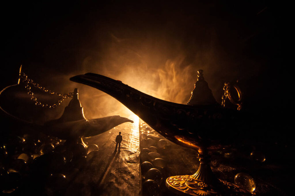 Koncept lampy přání. Silueta muže stojícího uprostřed silnice za mlhavé noci s obřím starožitným Aladdin arabských nocí Džin styl olejové lampy. Kreativní umělecká výzdoba - Fotografie, Obrázek