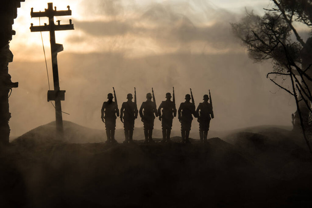 Oorlogsconcept. Militaire silhouetten vechtscène op oorlog mist lucht achtergrond, Wereldoorlog Soldaten Silhouet Onder bewolkt Skyline Bij zonsondergang. Strijd in verwoeste stad. Selectieve focus - Foto, afbeelding
