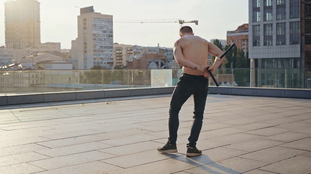 muscular man with tattoos exercising with nunchaku  - Кадры, видео