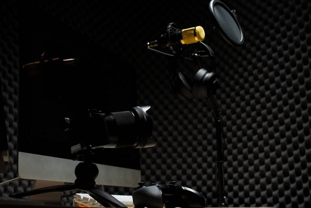 Condensador de micrófono, micrófono dorado cuelgan sobre la sala de pared absorbente de sonido con controlador de teclado del ratón del monitor de onda y auriculares en el estudio de audio oscuro, espacio de copia de fondo de iluminación de baja exposición
 - Foto, imagen