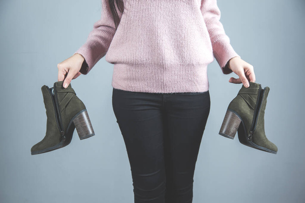 vrouw hand houden schoenen op grijze achtergrond - Foto, afbeelding
