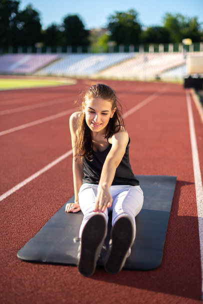 Κορίτσι αθλητής σε εξωτερικούς χώρους κάνει ασκήσεις ευελιξίας σε μια ηλιόλουστη μέρα - Φωτογραφία, εικόνα