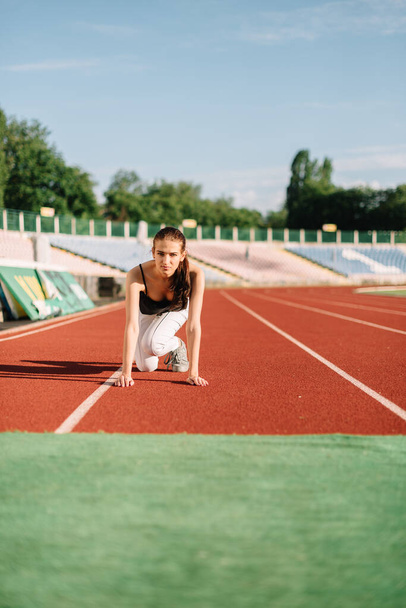 Dziewczyna sportowiec na bieżni na początku przed bieganiem - Zdjęcie, obraz