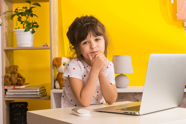 Online-koulu. Tyttö käyttää läppäriä. Etäopetus tai etäopetus. Lapsi tyttö opiskella verkossa hänen olohuoneessa. Covid-19-sepelvaltimovirus
. - Valokuva, kuva