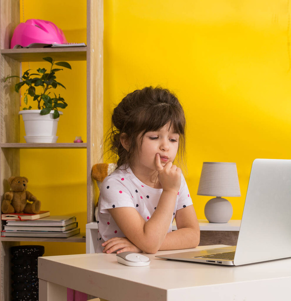 Online-Schule. Mädchen mit Laptop. Fernstudium oder Fernstudium. Mädchen lernen online in ihrem Wohnzimmer. Covid-19-Coronavirus. - Foto, Bild