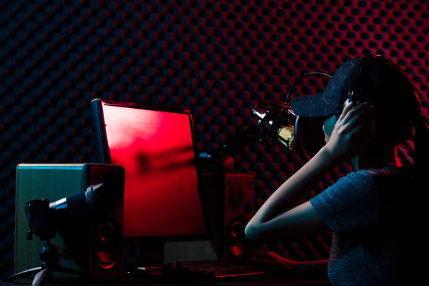 Young Adult is DJ VJ online station. Woman connect social media with professional equipment such as e-sport gaming keyboard, mouse, monitor, speaker, camera,  microphone studio, dark red blue theme - Фото, зображення