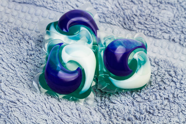 Three washing machine detergent pods on a blue towel in a close up view - Photo, Image