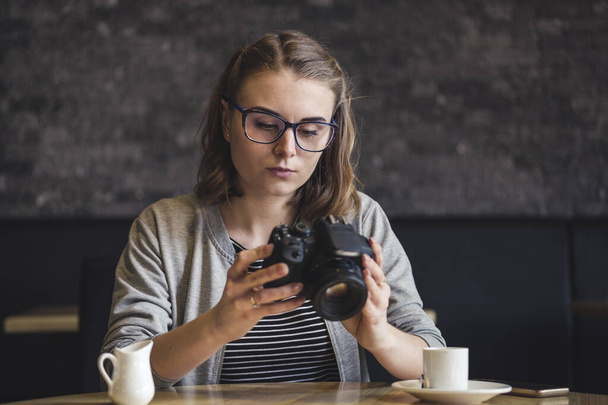 Fiatal női fotós ellenőrzi a képet, ahogy ellazul  - Fotó, kép